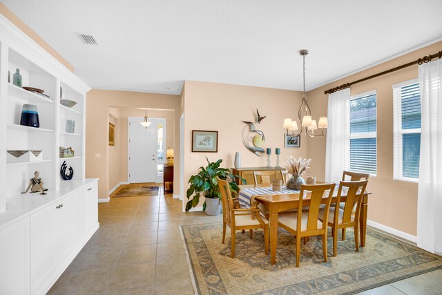 tiled dining area featuring built in shelves and a notable chandelier