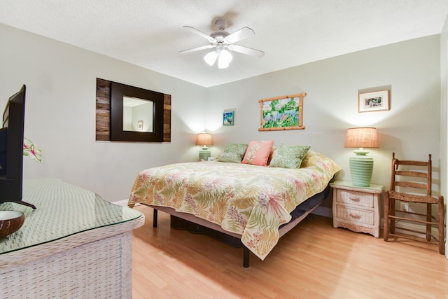 bedroom featuring light wood-type flooring, ceiling fan, and a textured ceiling