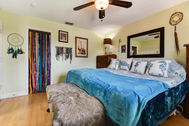 bedroom with a textured ceiling, ceiling fan, and light hardwood / wood-style flooring