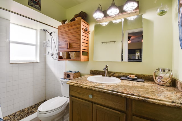 bathroom with a tile shower, vanity, and toilet