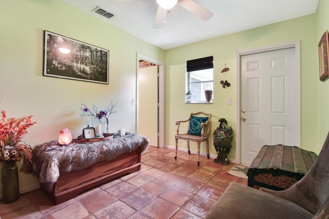 living room featuring ceiling fan and a textured ceiling