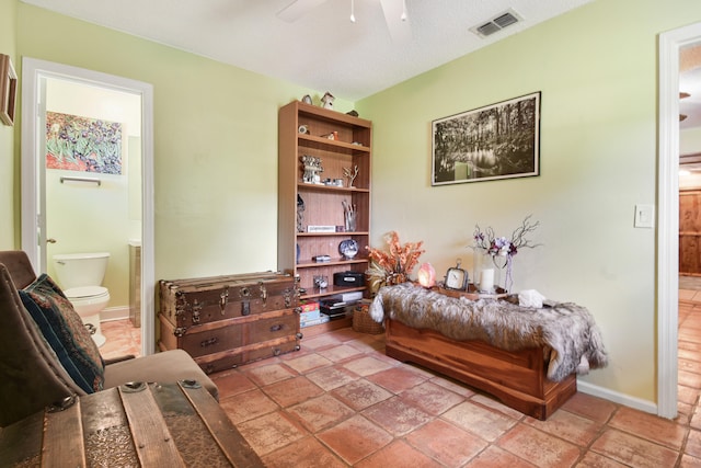 living area featuring ceiling fan and a textured ceiling