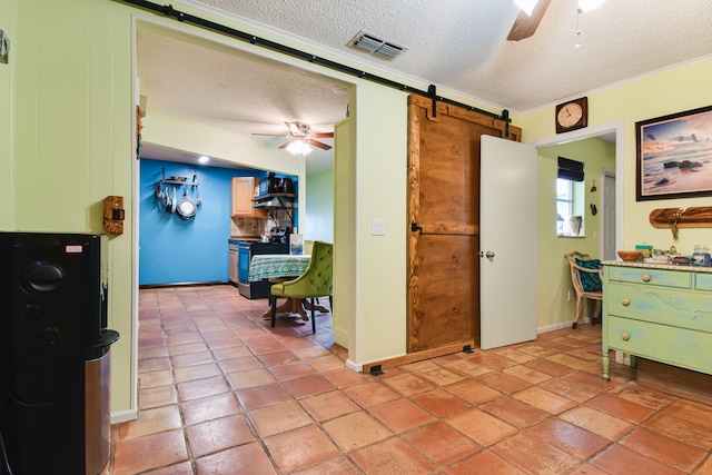 interior space featuring a barn door, crown molding, and a textured ceiling