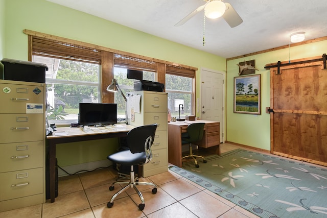 home office with ceiling fan, light tile patterned floors, and a barn door