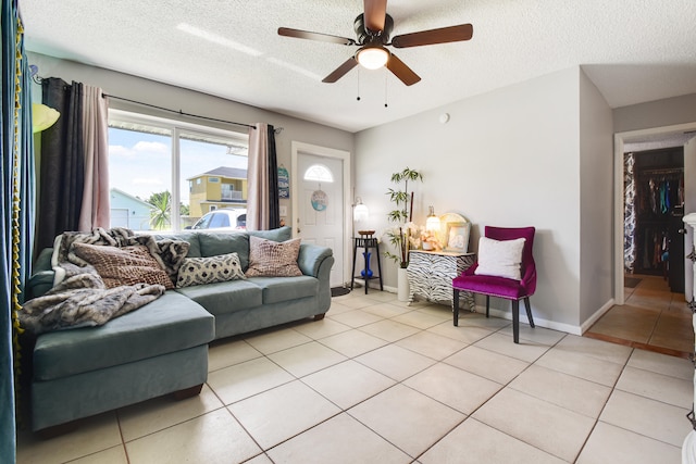 living room with a textured ceiling, light tile patterned floors, and ceiling fan