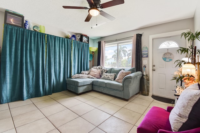 living room with ceiling fan, light tile patterned floors, and a textured ceiling