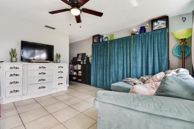 living room with a textured ceiling, ceiling fan, and light tile patterned floors