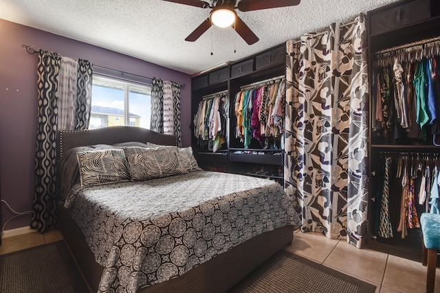 tiled bedroom featuring ceiling fan, a textured ceiling, and a closet