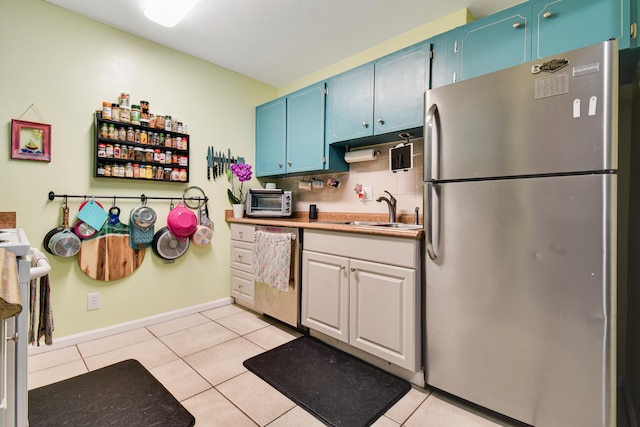 kitchen with appliances with stainless steel finishes, light tile patterned floors, and blue cabinetry