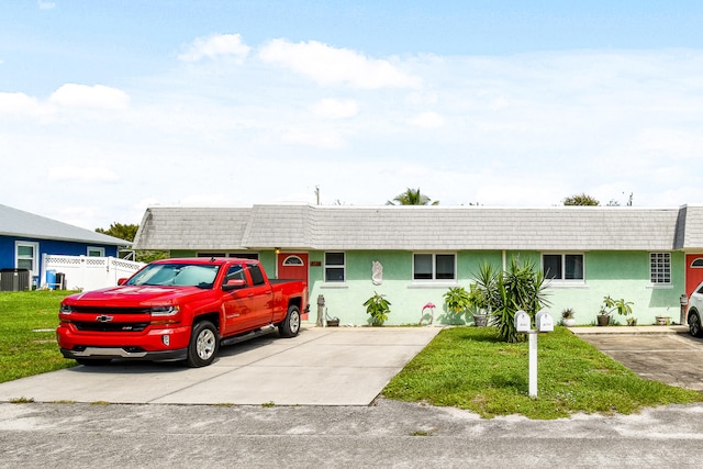 ranch-style home featuring a front lawn and central AC unit