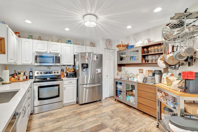 kitchen with light hardwood / wood-style flooring, stainless steel appliances, sink, and white cabinetry