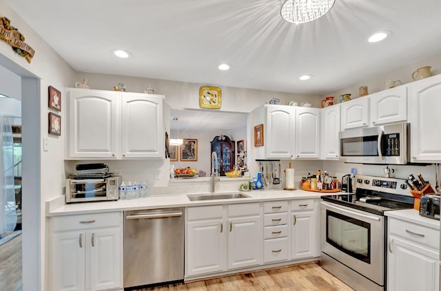 kitchen with appliances with stainless steel finishes, light hardwood / wood-style floors, sink, and white cabinets