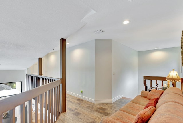 corridor featuring light wood-type flooring and a textured ceiling