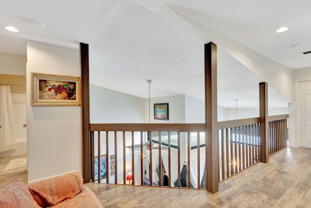 hall with vaulted ceiling and light hardwood / wood-style floors