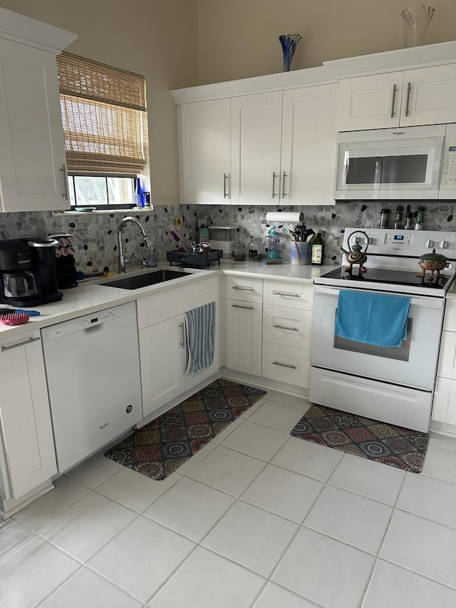 kitchen featuring backsplash, a sink, light countertops, white appliances, and white cabinetry