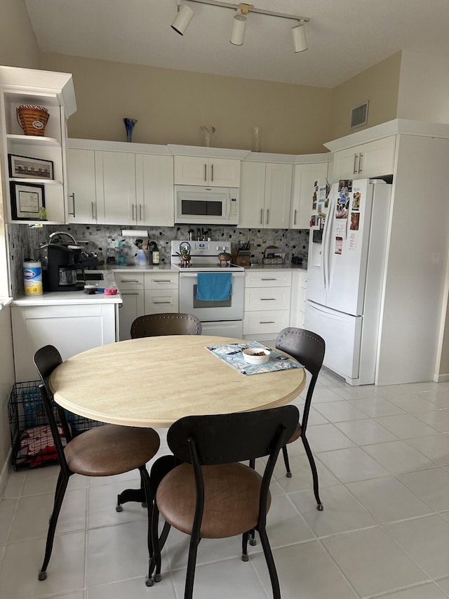 kitchen with decorative backsplash, white appliances, white cabinetry, and visible vents
