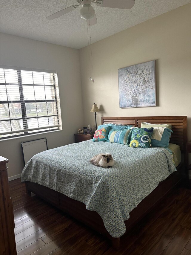bedroom with a textured ceiling, ceiling fan, baseboards, and wood finished floors