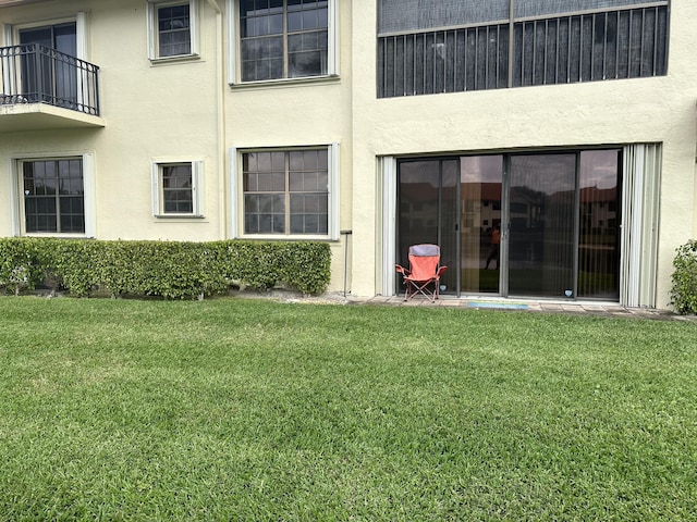 rear view of property with stucco siding and a yard