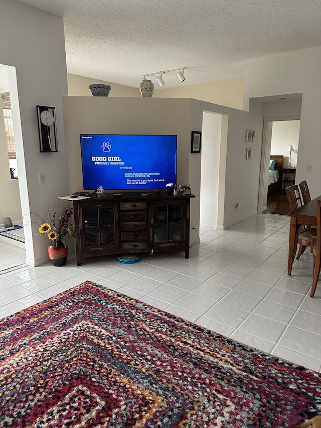 living area featuring a textured ceiling, tile patterned floors, and vaulted ceiling