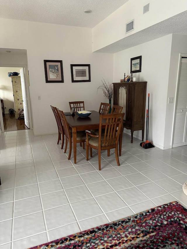 dining room with light tile patterned flooring, a textured ceiling, and visible vents