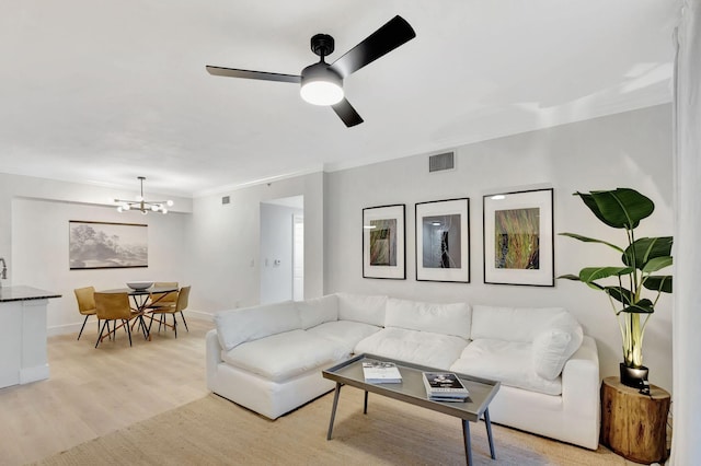 living room featuring ceiling fan with notable chandelier, ornamental molding, and light hardwood / wood-style flooring