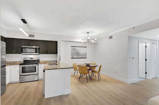 kitchen with appliances with stainless steel finishes, light wood-type flooring, and pendant lighting