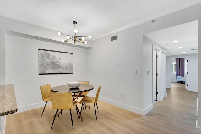 dining area featuring light hardwood / wood-style flooring, a notable chandelier, and crown molding