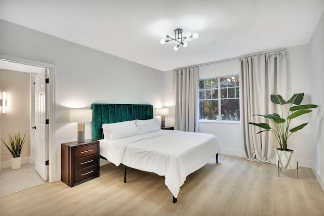 bedroom featuring light wood-type flooring and a chandelier