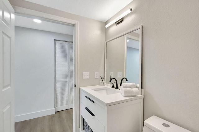 bathroom with vanity, toilet, and hardwood / wood-style flooring