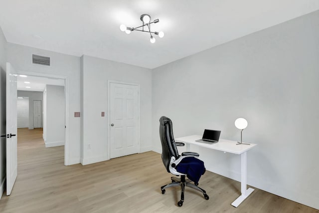 home office with a chandelier and light hardwood / wood-style floors