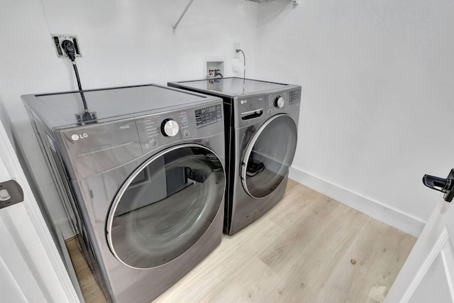 laundry area featuring light wood-type flooring and washer and clothes dryer