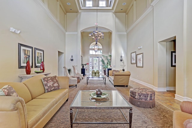 living room with a towering ceiling, a chandelier, and plenty of natural light