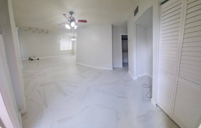 spare room featuring baseboards, visible vents, a ceiling fan, marble finish floor, and rail lighting