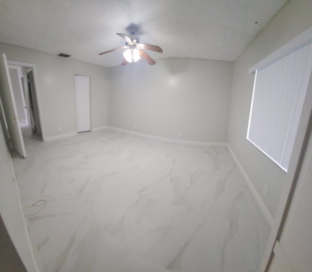 spare room featuring ceiling fan, marble finish floor, visible vents, and baseboards