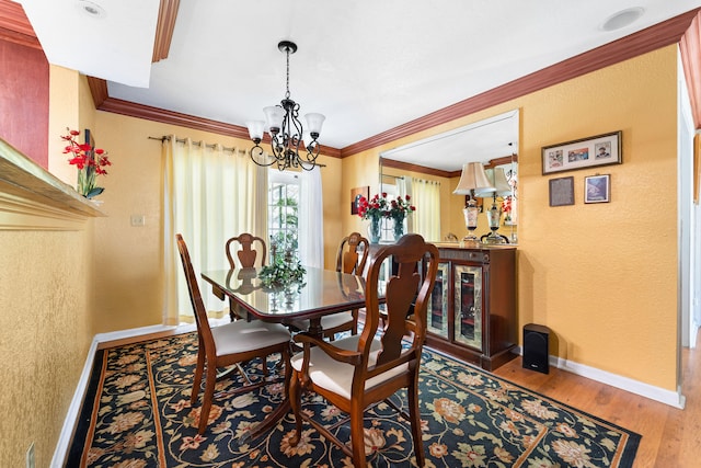 dining area with ornamental molding, hardwood / wood-style floors, and a chandelier