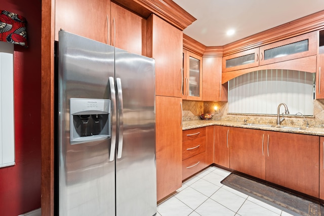 kitchen featuring decorative backsplash, stainless steel refrigerator with ice dispenser, light stone counters, and sink