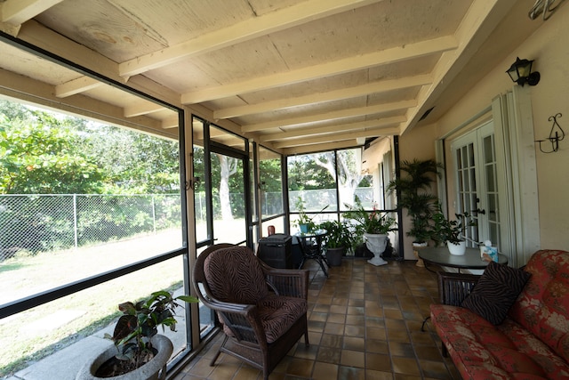 sunroom / solarium featuring beam ceiling, plenty of natural light, and french doors