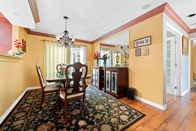 dining space with a notable chandelier, crown molding, and hardwood / wood-style flooring