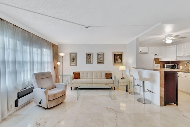 living room with heating unit, ceiling fan, and a textured ceiling