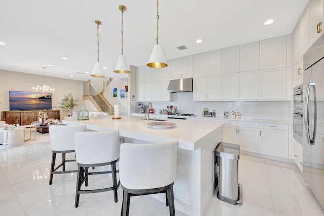 kitchen featuring a kitchen bar, a large island, decorative light fixtures, white cabinets, and an inviting chandelier