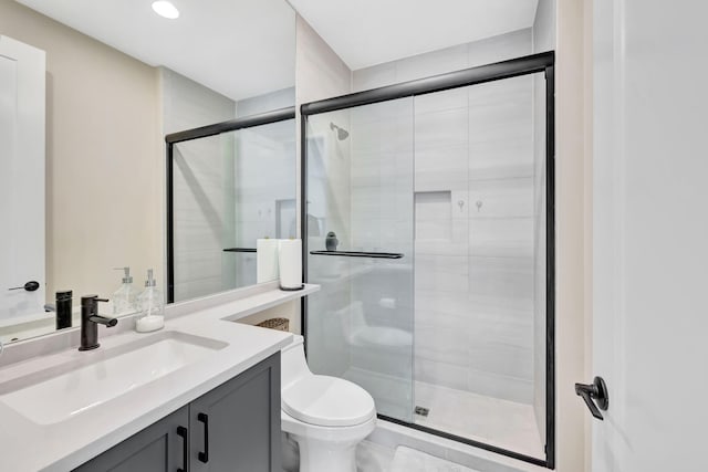 bathroom with toilet, an enclosed shower, and vanity