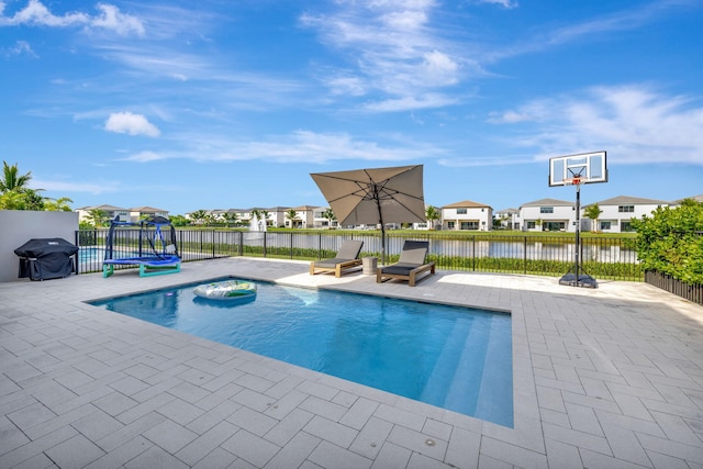 view of pool featuring a patio, a grill, and a water view