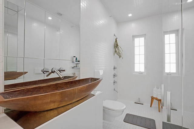 bathroom with tile walls, tile patterned flooring, tiled shower, vanity, and toilet