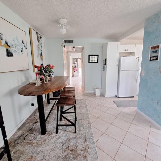 tiled dining space with ceiling fan and a textured ceiling