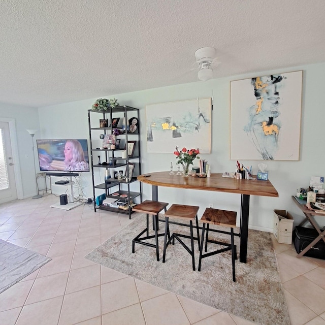 dining space featuring ceiling fan, light tile patterned floors, and a textured ceiling