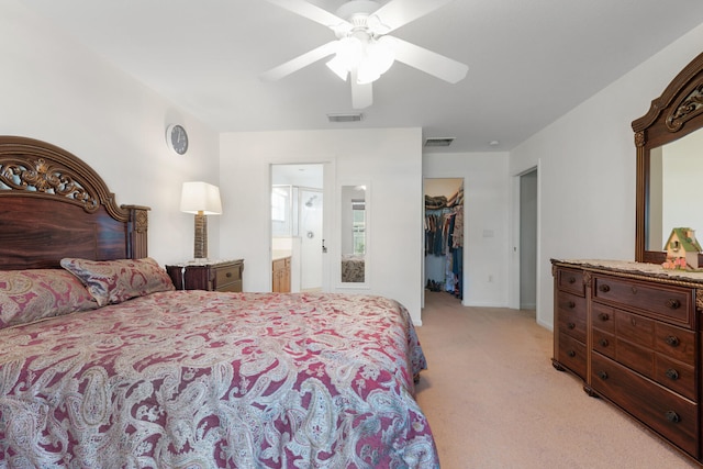 carpeted bedroom with a closet, ensuite bath, ceiling fan, and a walk in closet