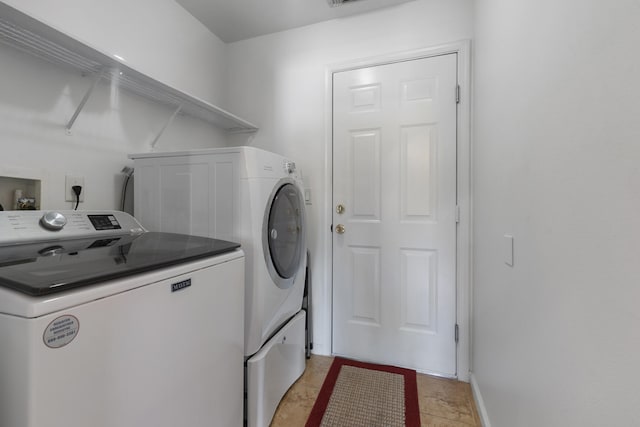 clothes washing area with light tile patterned floors and washer and dryer