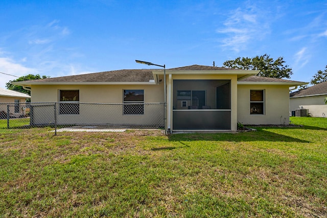 rear view of house with a lawn, a sunroom, and central AC