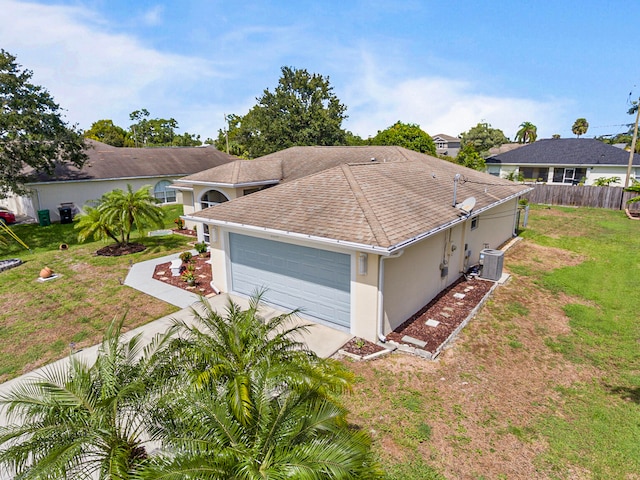 exterior space with a garage, a front lawn, and central air condition unit