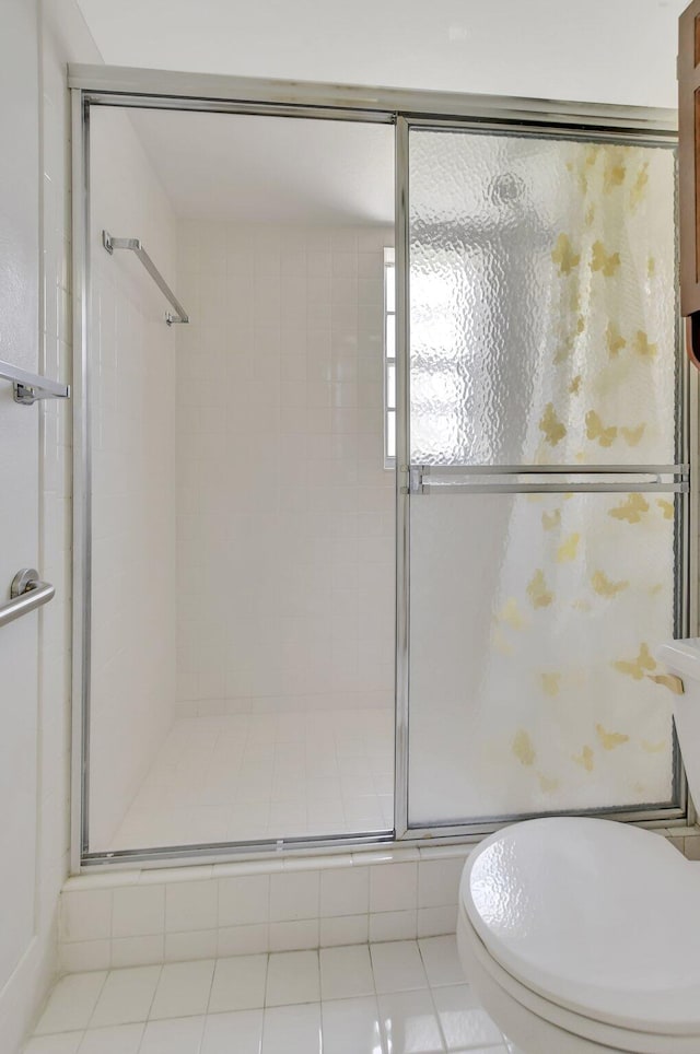 bathroom with tile patterned flooring, a shower with shower door, and toilet